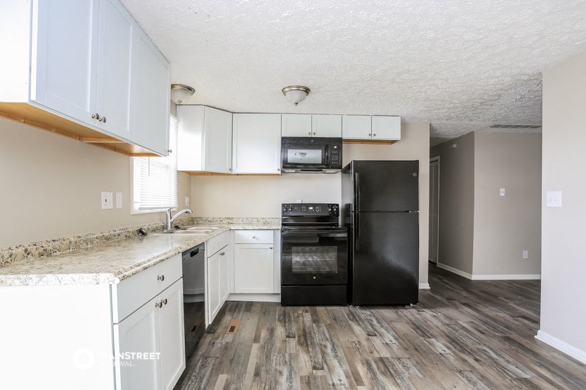 a kitchen with white cabinets and a black refrigerator