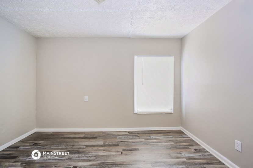 the living room of an apartment with wood flooring and a window