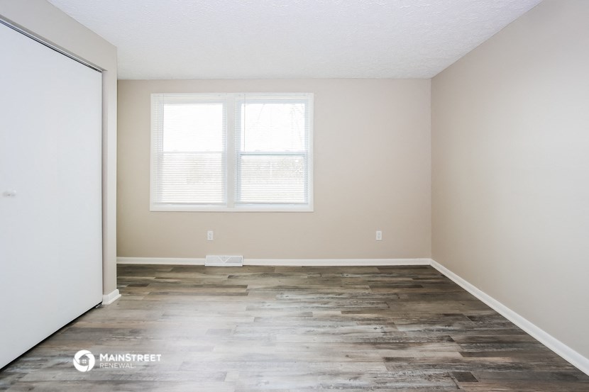 an empty room with wood floors and a window