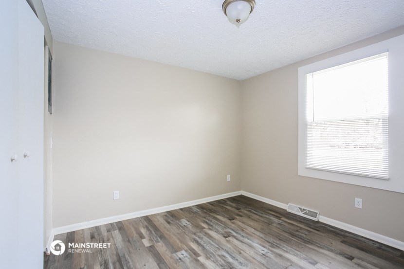 the living room of an apartment with wood flooring and a window
