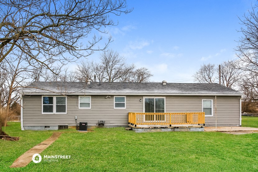 a gray house with a yellow deck on a grassy yard