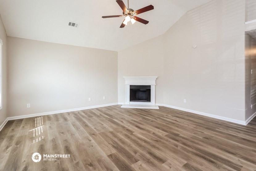 the living room with wood flooring and a ceiling fan