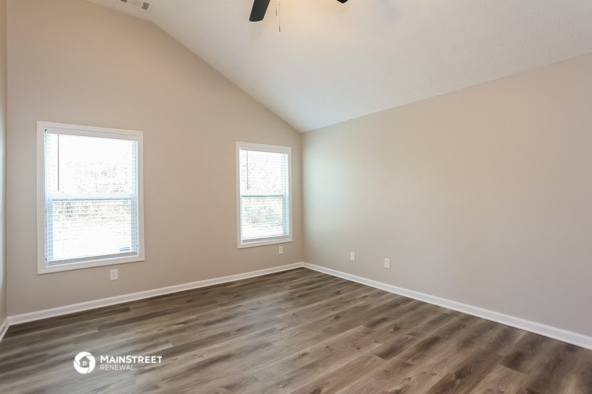 the spacious living room with hardwood flooring and two windows