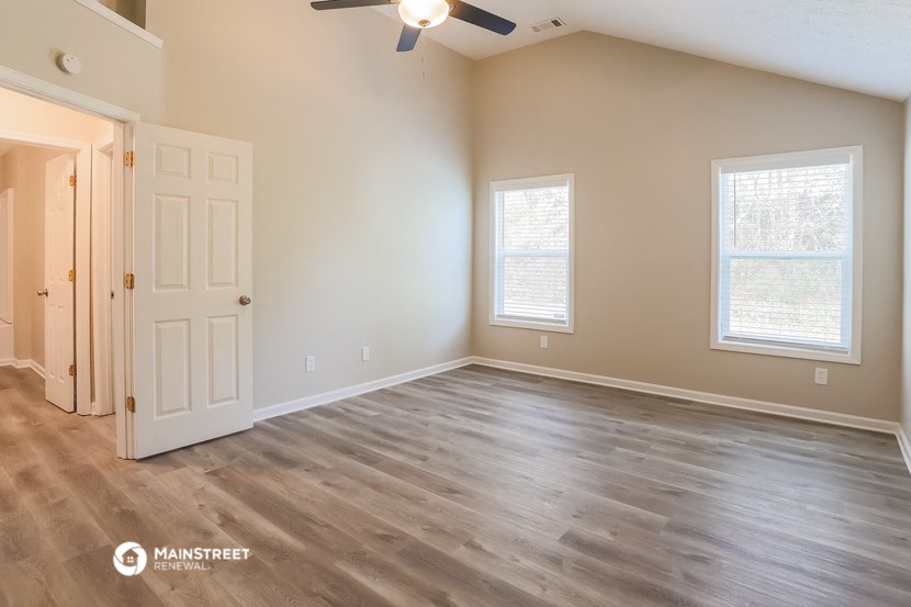 the spacious living room with wood flooring and a ceiling fan