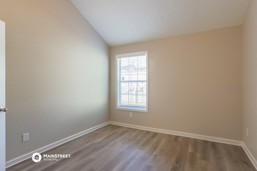the spacious living room with hardwood flooring and a window