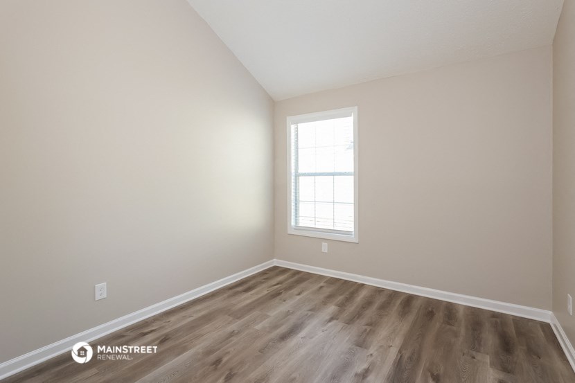 the spacious living room with hardwood flooring and a window