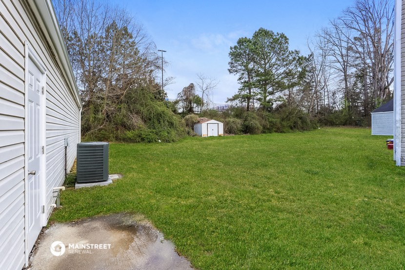 a backyard with a white house and a green lawn