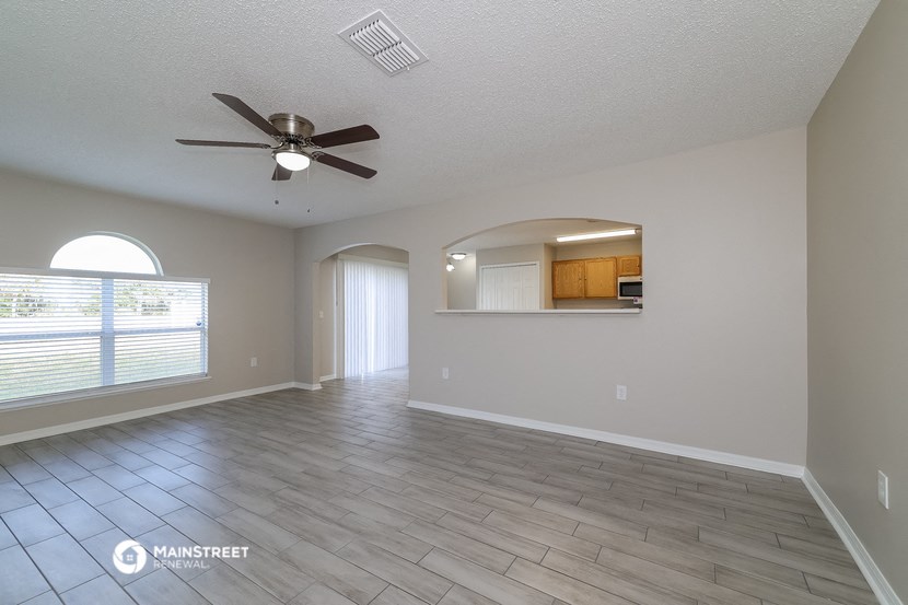 an empty living room with a ceiling fan and a window