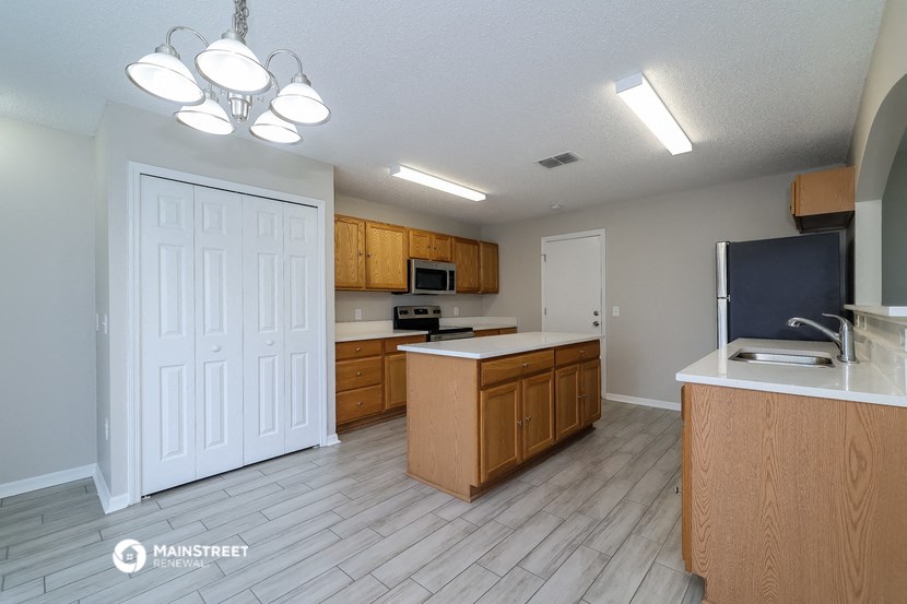 an empty kitchen with wood flooring and wooden cabinets