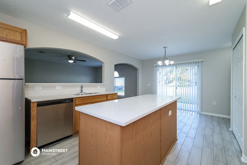 a kitchen with a white counter top and a sliding glass door