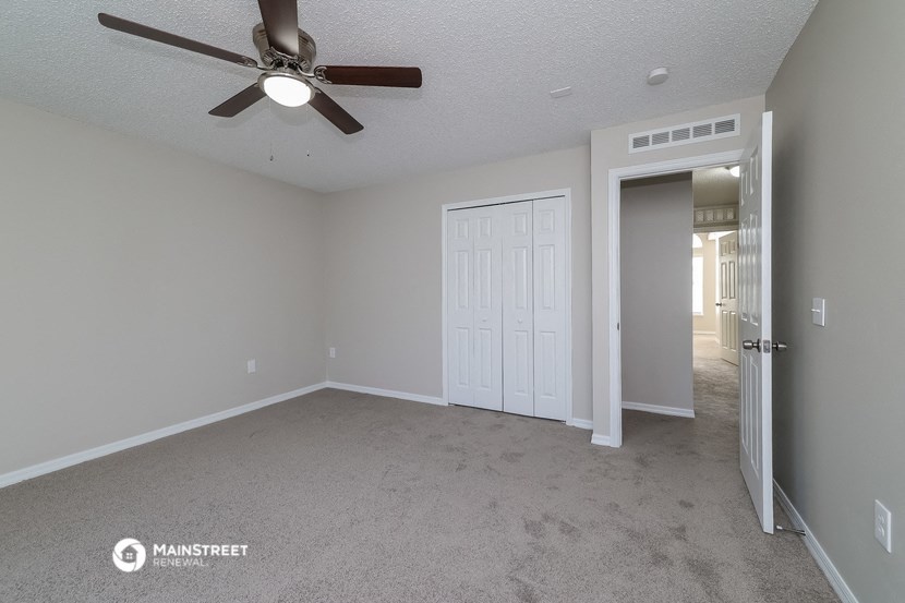 the living room of an empty house with a ceiling fan