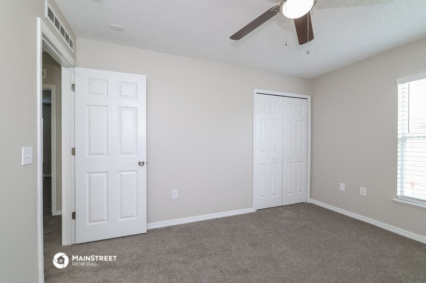 a bedroom with two white doors and a ceiling fan