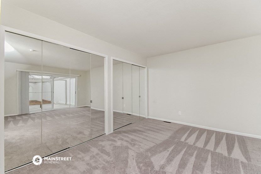 a living room with mirrors on the wall and a carpeted floor