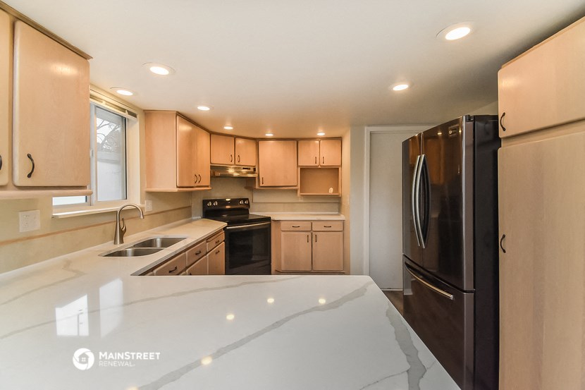 a kitchen with a white counter top and a black refrigerator