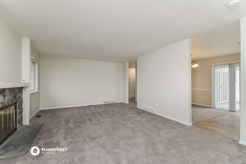 the living room and dining room of an apartment with a fireplace