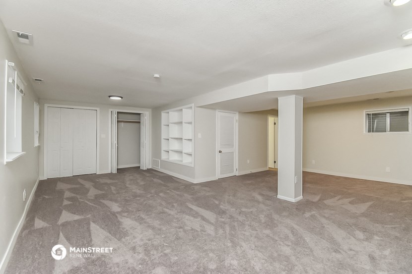 an empty living room with white cabinets and a gray floor
