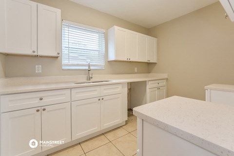 a kitchen with white cabinets and white counter tops and a sink