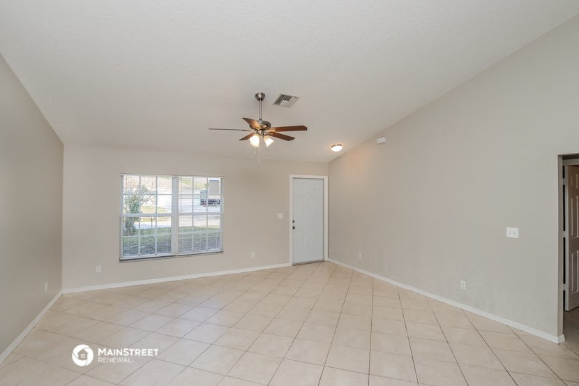 the living room of an empty house with a ceiling fan