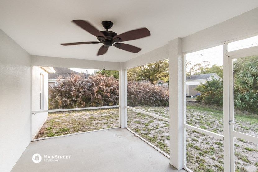 a screened in porch with a ceiling fan and glass doors