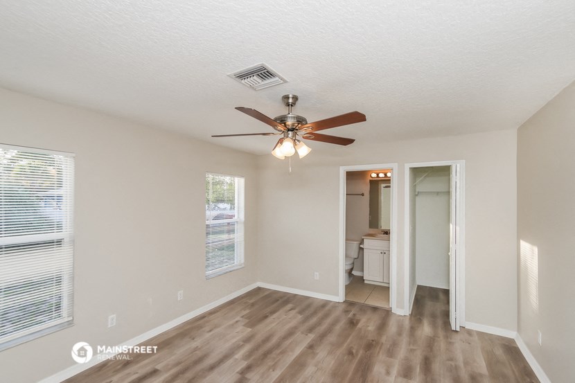 a living room with a ceiling fan and a door to a bathroom