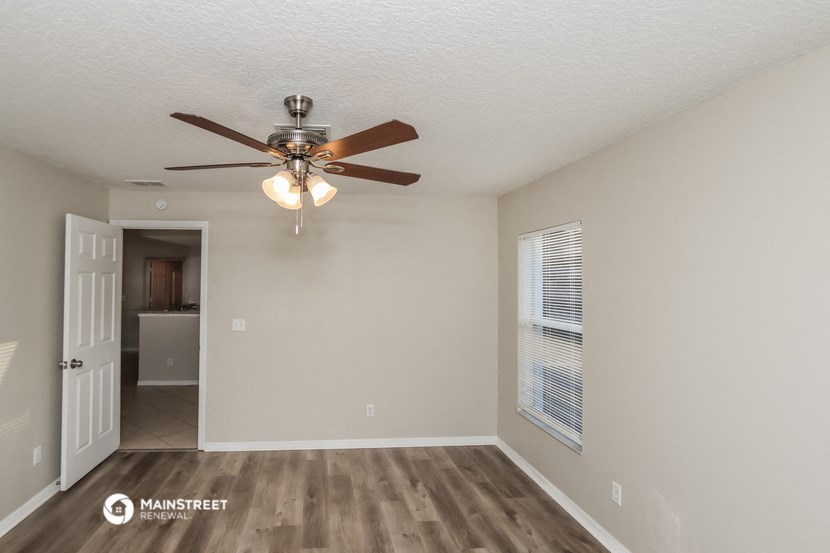 a living room with a ceiling fan and a door to a kitchen