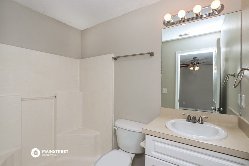 a bathroom with a toilet sink and mirror and a shower
