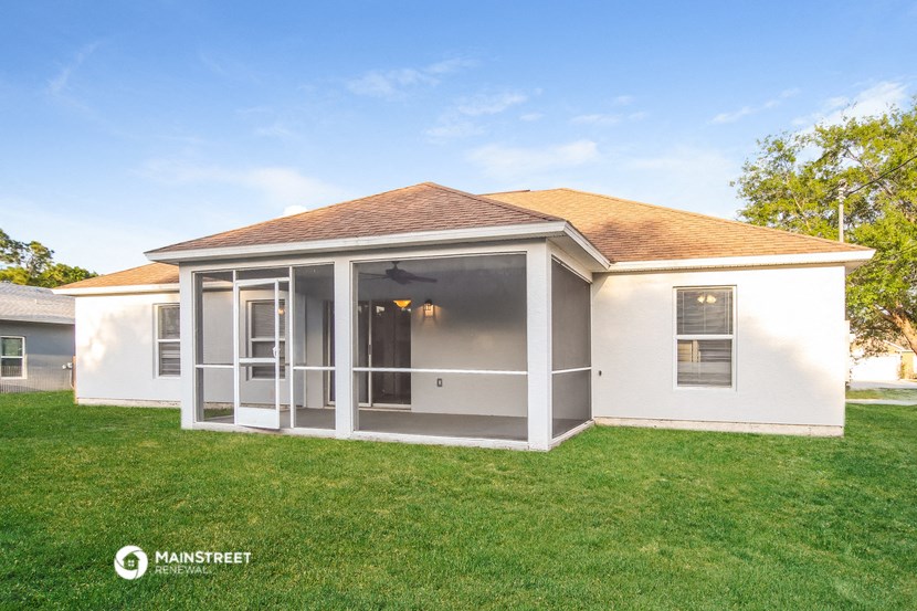 a small white house with a porch and a lawn