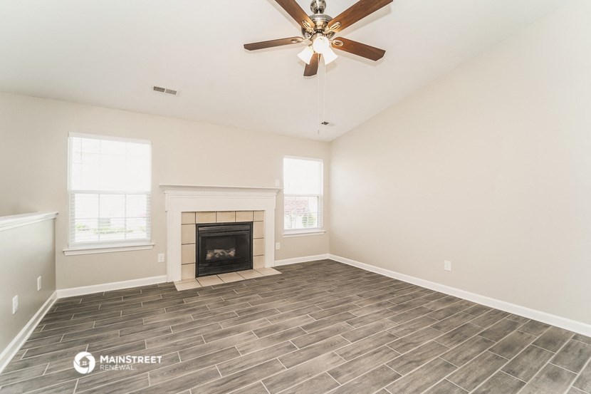a living room with a fireplace and a ceiling fan
