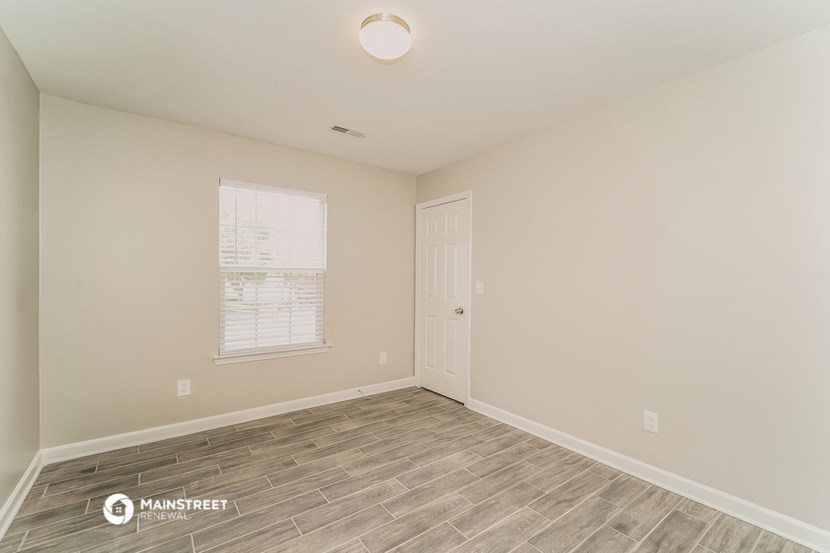 the spacious living room with wood flooring and a window