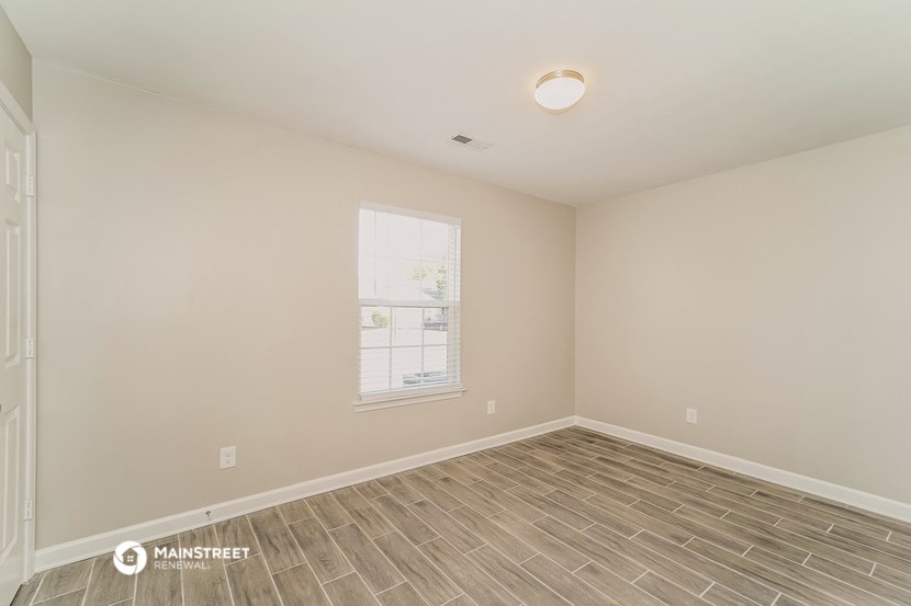 the spacious living room with wood flooring and a window