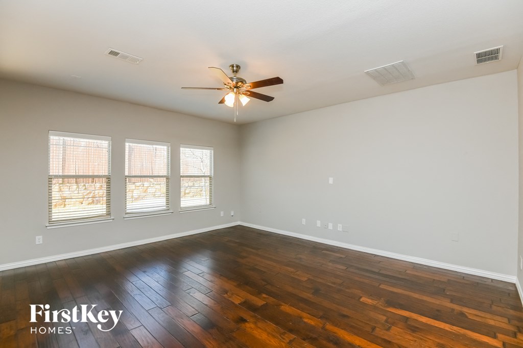 an empty living room with wood floors and a ceiling fan