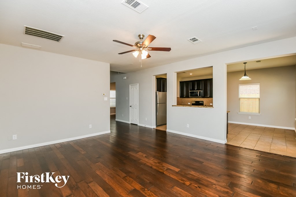 an empty living room with wood flooring and a ceiling fan