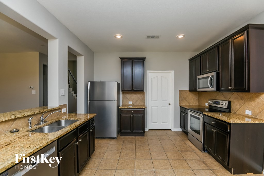 a kitchen with black cabinets and granite counter tops and stainless steel appliances