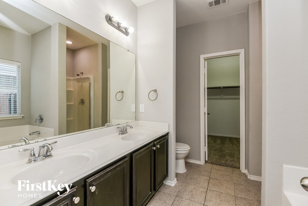 a bathroom with a large mirror and two sinks and a toilet