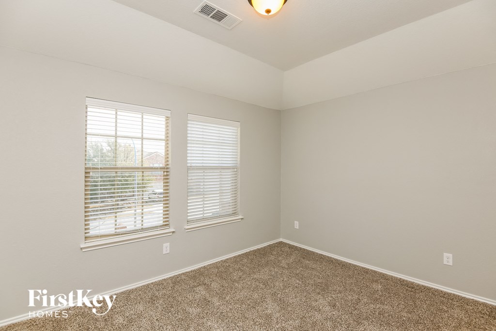 the second bedroom is spacious and has a carpeted floor and two windows