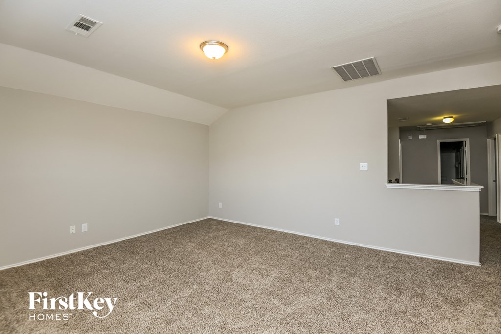 a spacious living room with carpet and white walls