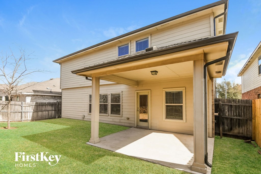 the back of a white house with a patio and a yard