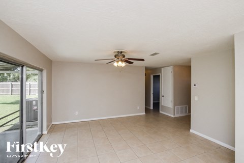 A spacious room with a ceiling fan and sliding glass doors.