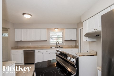 A kitchen with a stove top oven and white cabinets.