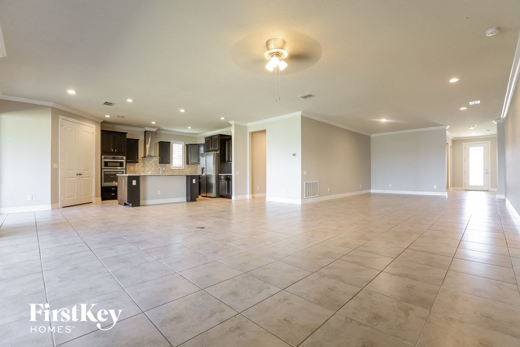 an empty living room with a large tile floor and a kitchen