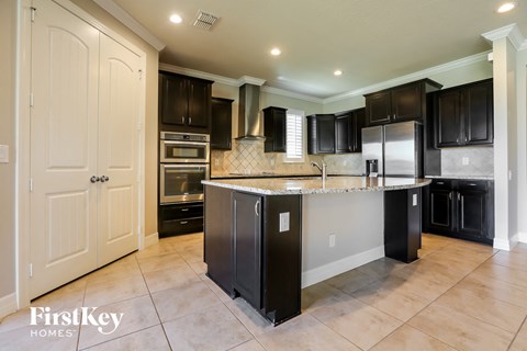 a large kitchen with black cabinets and stainless steel appliances