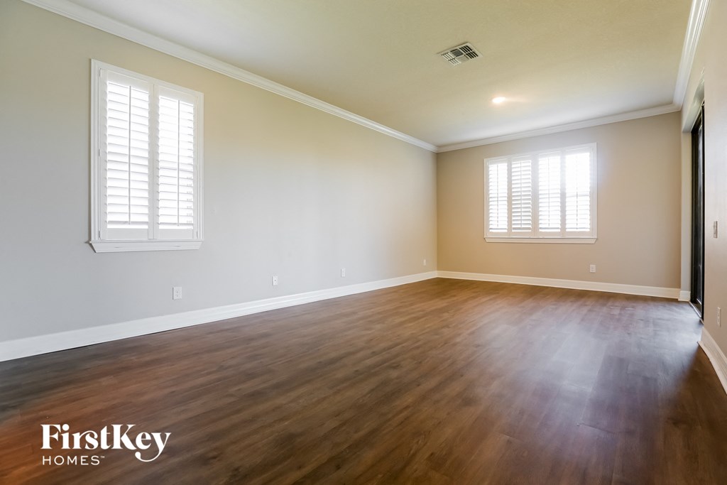 the living room with hardwood flooring and white walls and windows