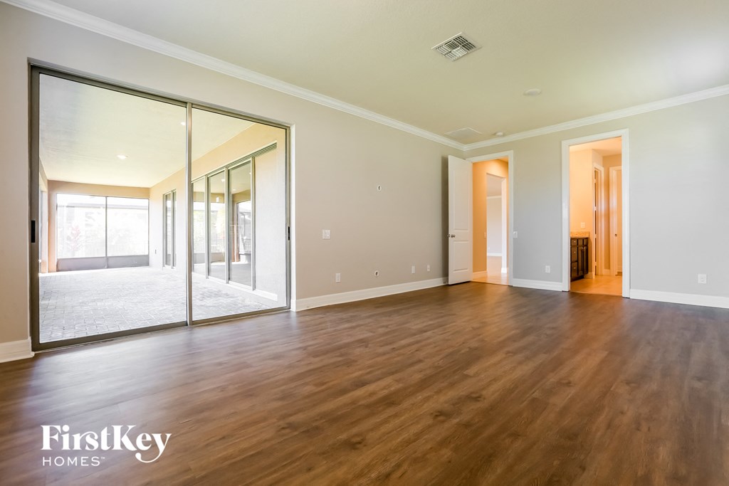 an empty living room with wood flooring and large windows