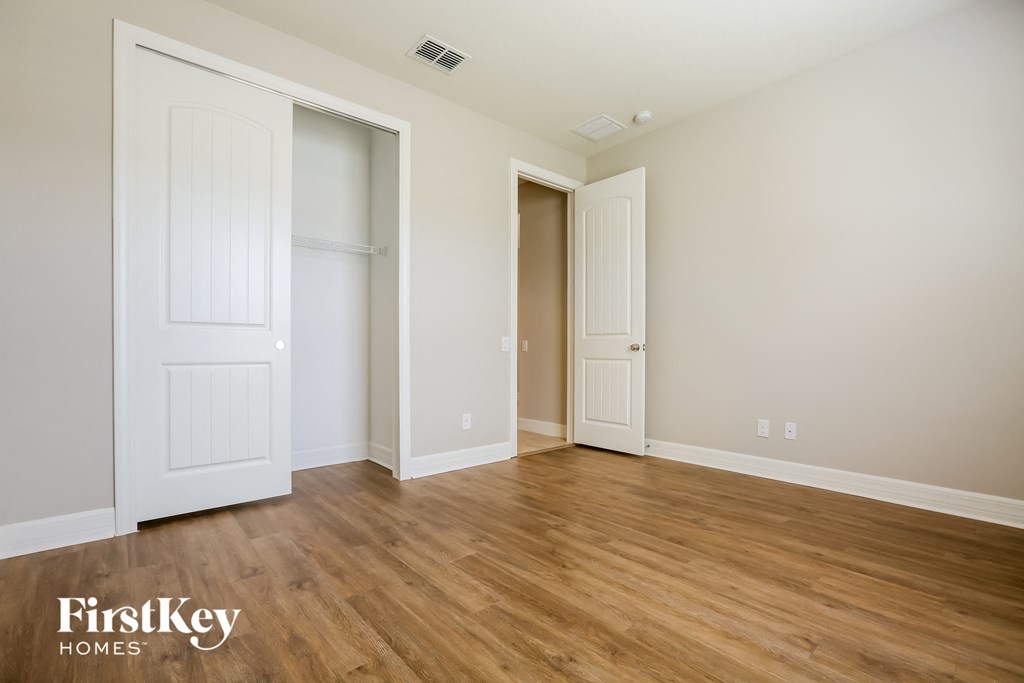 a bedroom with white walls and wood flooring and two closets
