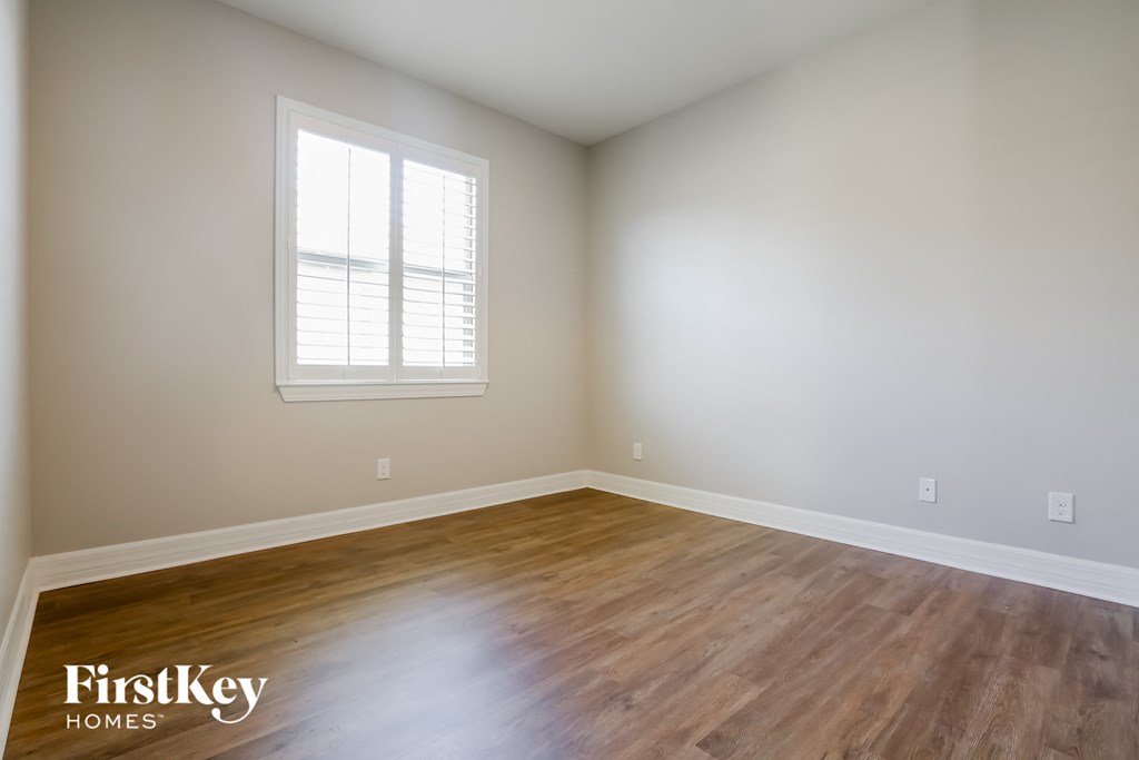 the spacious living room with hardwood flooring and a window