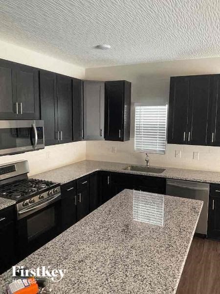 A kitchen with black cabinets and a granite countertop.