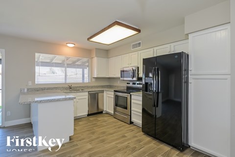 A kitchen with a black refrigerator and wooden floors.