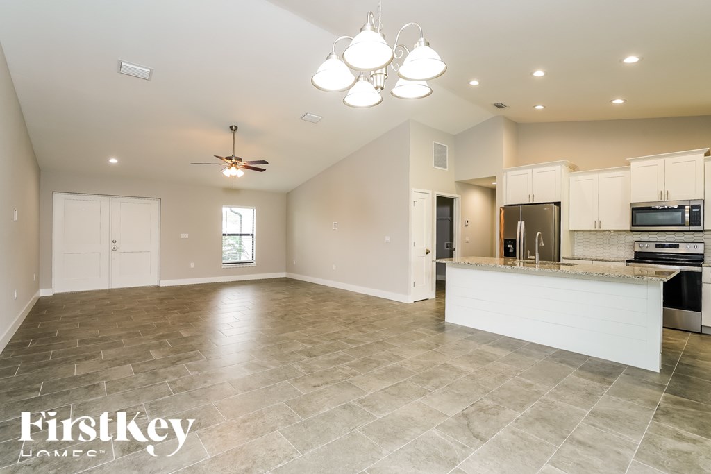 A spacious kitchen and living room with a tiled floor and a ceiling fan.