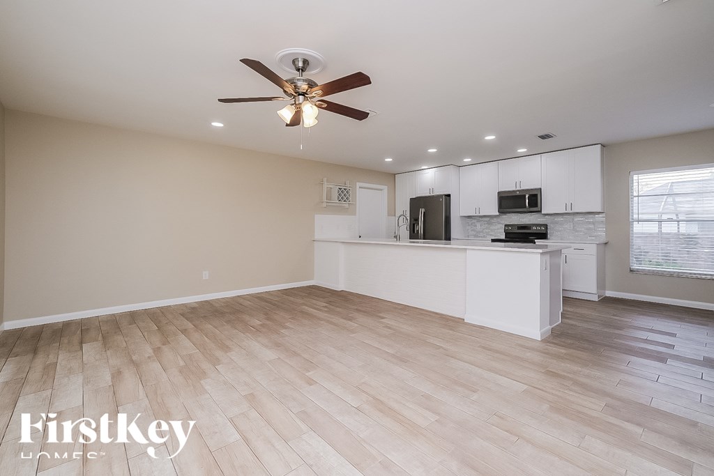 a kitchen and living room with wood floors and a ceiling fan