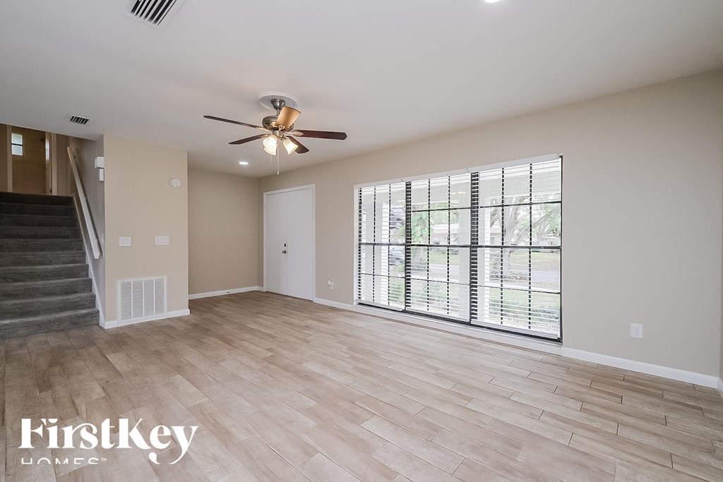 an empty living room with a ceiling fan and a large window